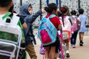 A kindergarten student gives a thumbs up to his parents as he heads to the first day of class.