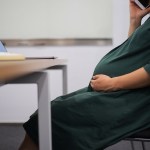 Pregnant woman sitting at a desk at work.