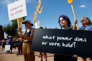 People hold signs referencing voting at a Women's March rally outside the State Capitol in Phoenix, Arizona.