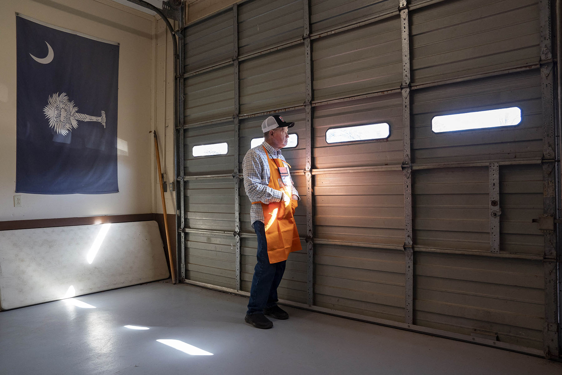 A poll worker looks out a garage window at a polling location.