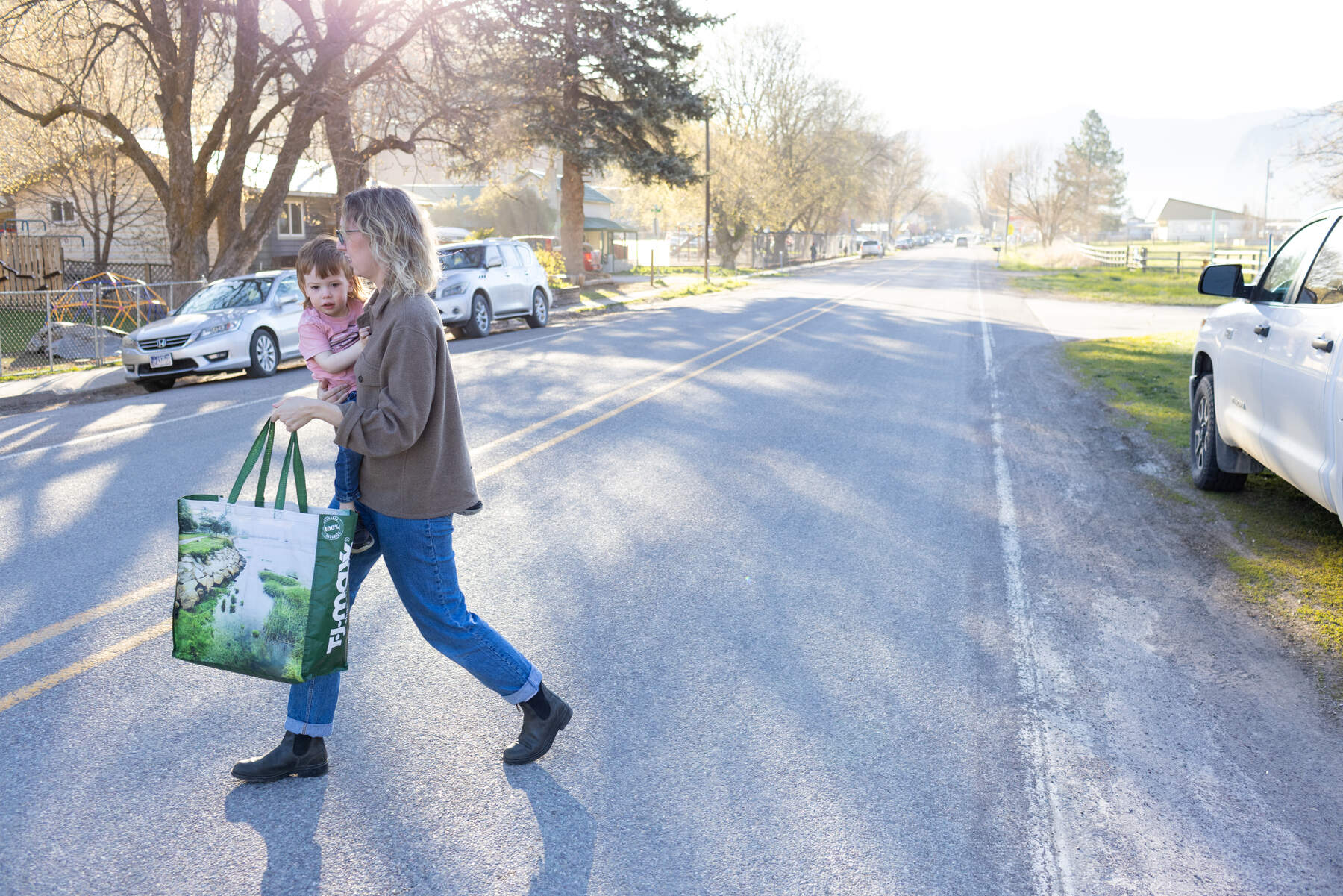 A woman carries her 3-year-old son across the street.