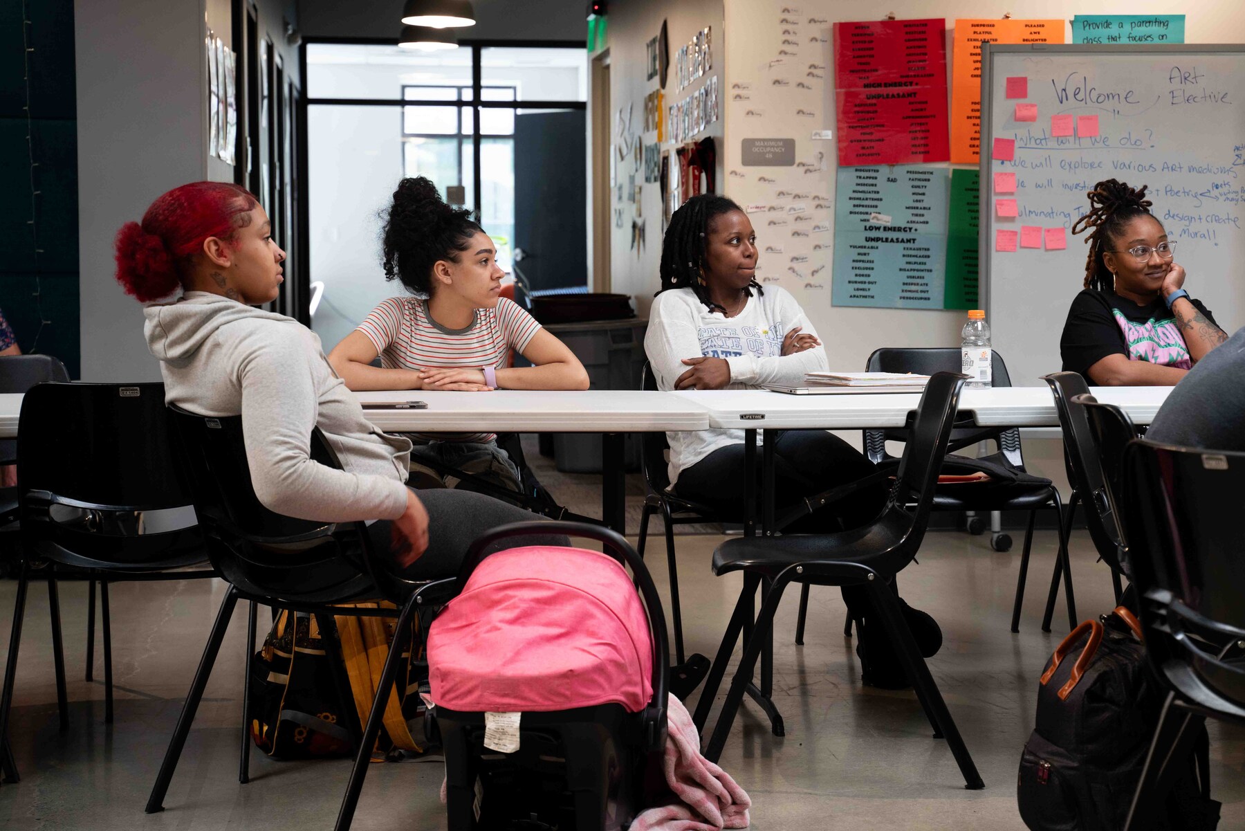 Four adults sit in a classroom.