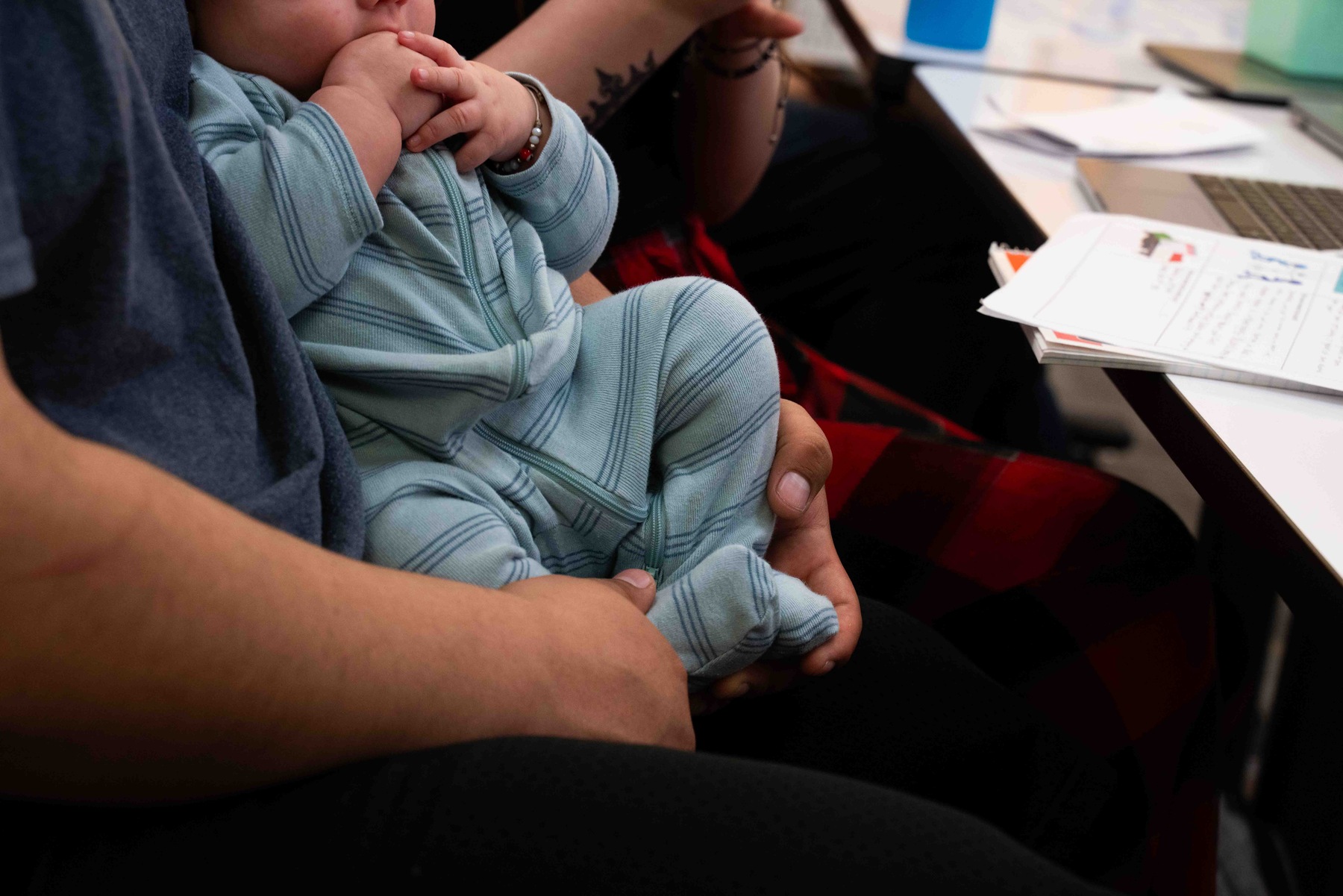 Rene, a senior at Lumen High School, holds his newborn son, RJ, during class.