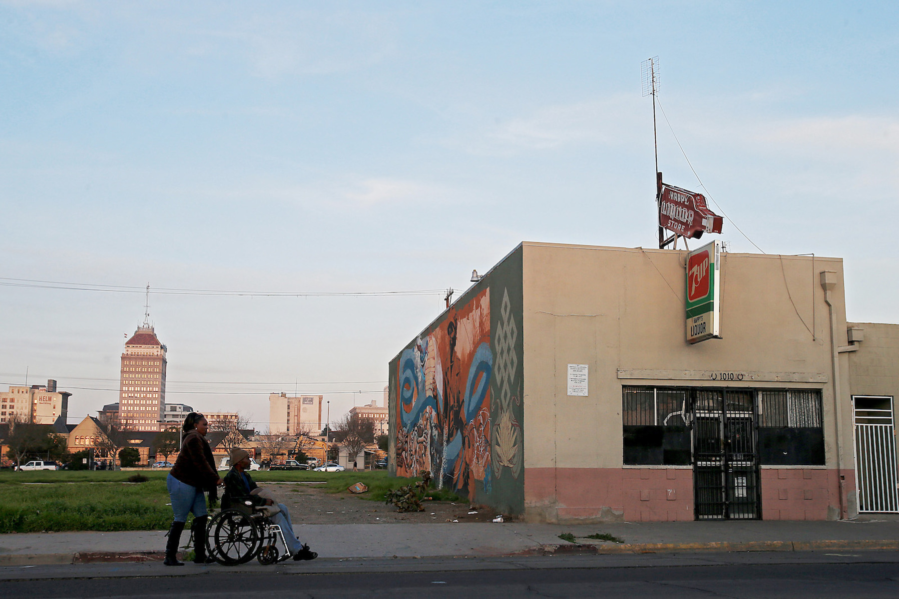 A woman pushes a person in a wheelchair along a street in Fresno, California.