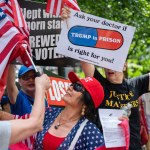 Protesters hold American flags and signs about Trump