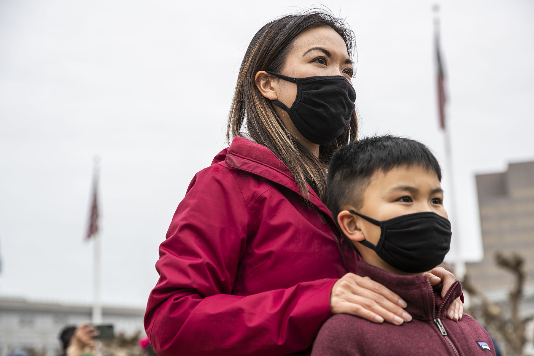 A mother stands behind her son as they attend a rally together.