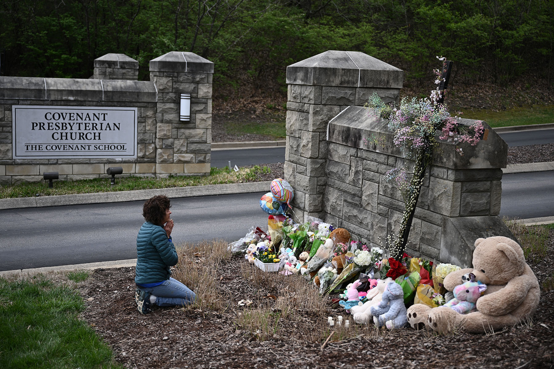 A person prays at a makeshift memorial for victims outside the Covenant School building.