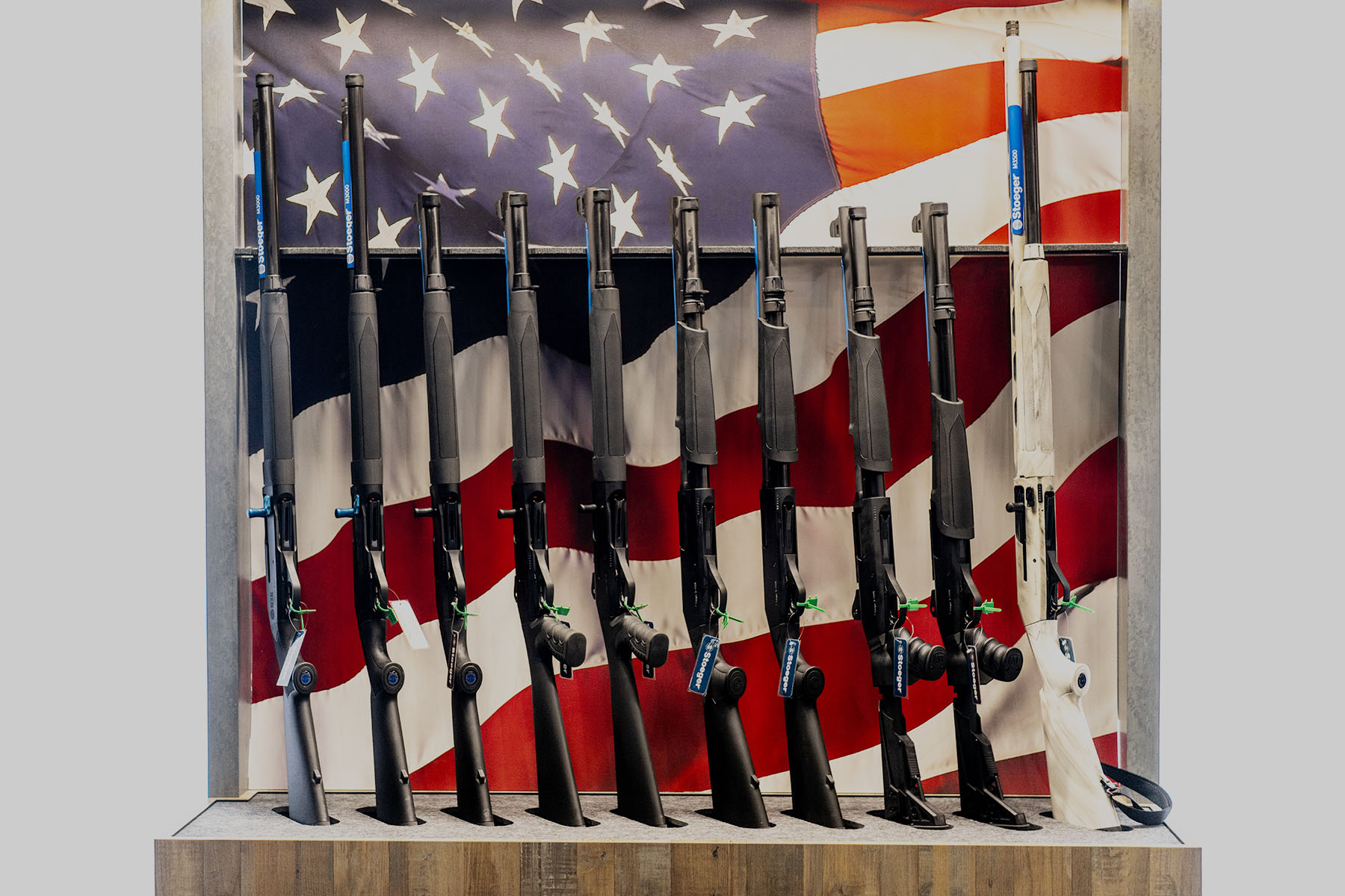 Firearms are seen on display during the National Rifle Association's annual convention. Behind the firearms, a picture of an American flag is displayed.