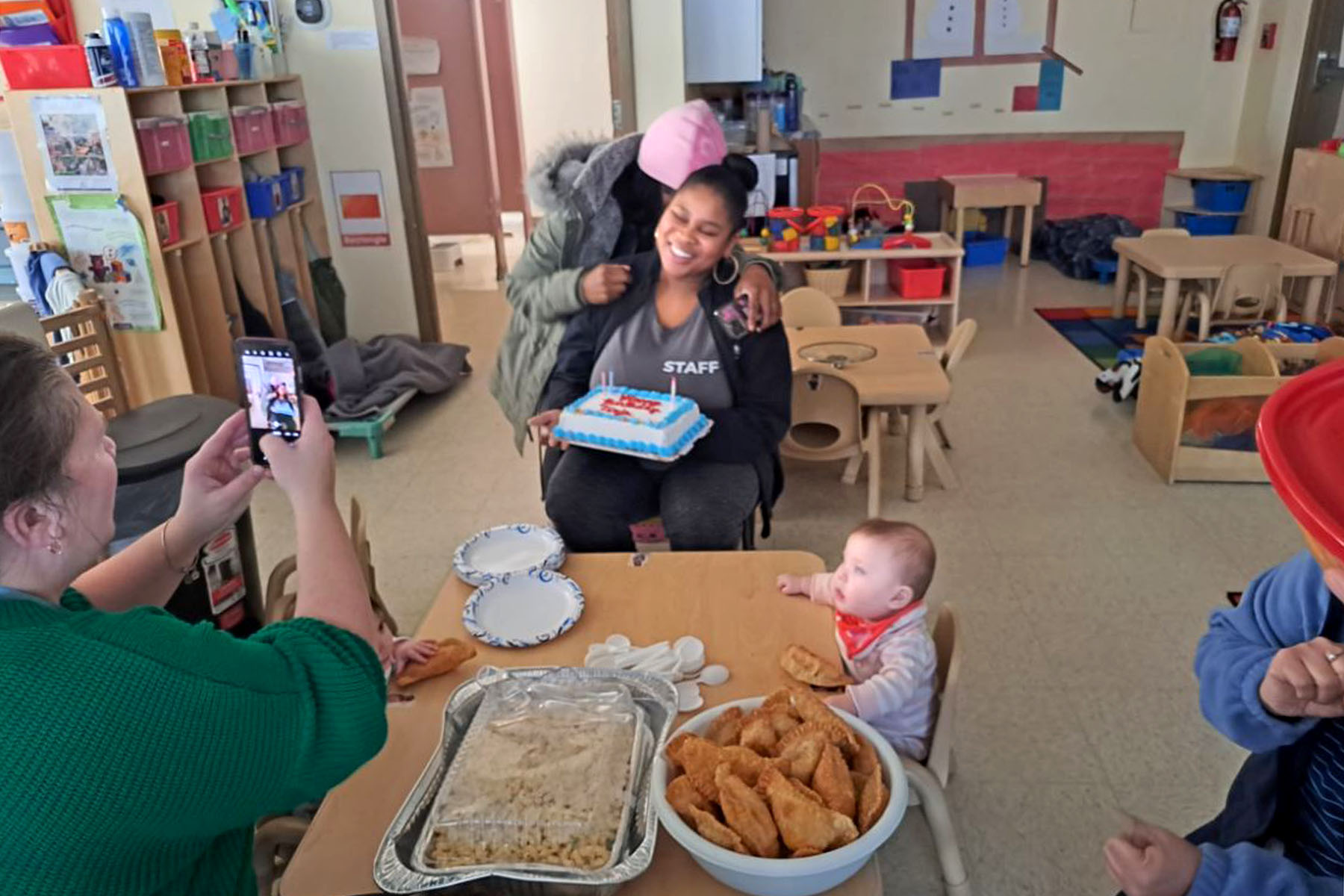 Tiaja Gundy holds a birthday cake in a classroom.