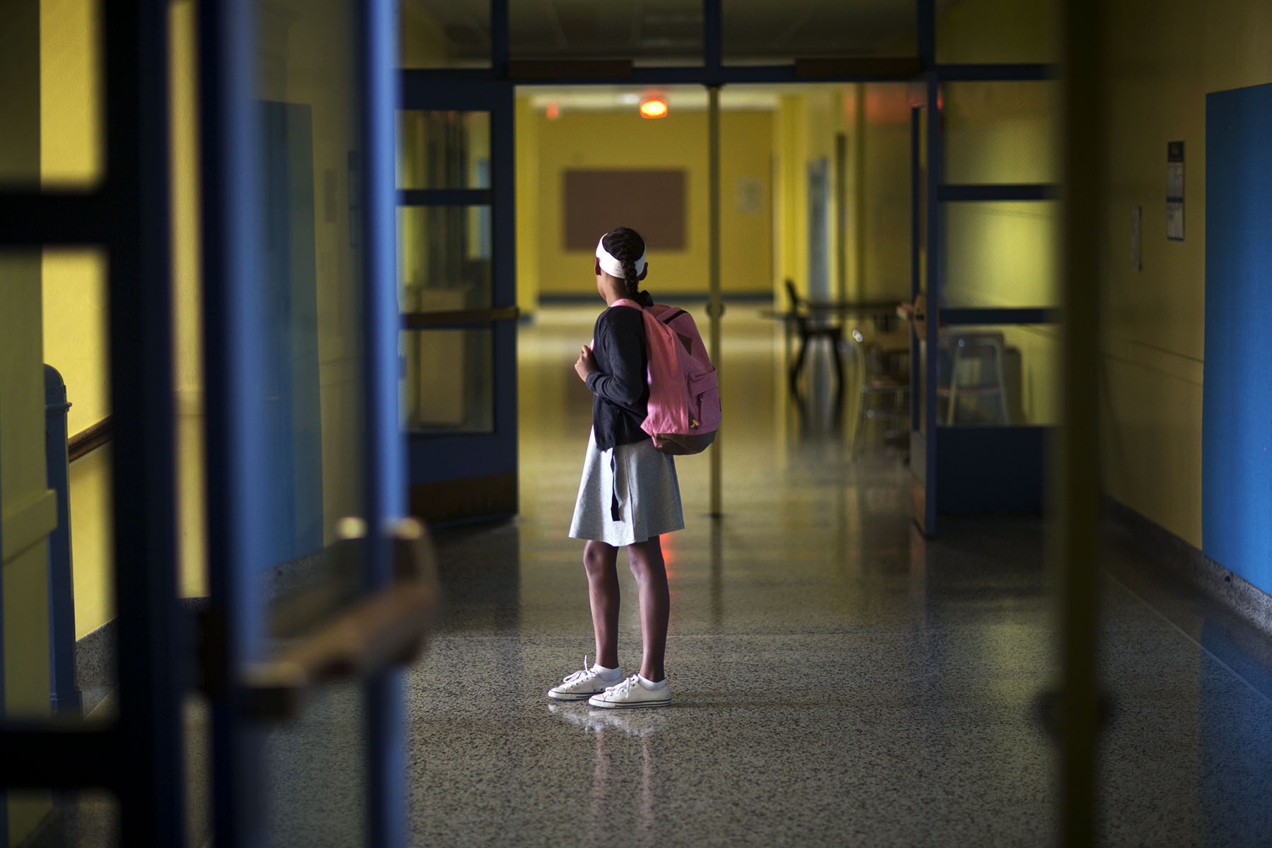 A girl stands in school hallway.