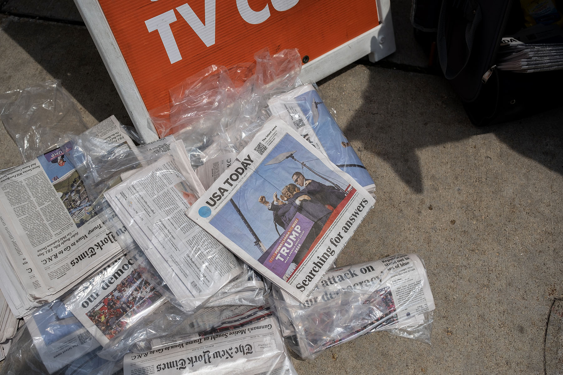 Newspapers lay on the ground in Milwaukee, Wisconsin. The front page of USA Today is seen with a photo of Trump being escorted off stage after an assassination attemp with the headline "Searching for Answers."