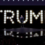 Former President Donald Trump arrives to speak on stage on the fourth day of the Republican National Convention. Behind him, spotlights spells out 