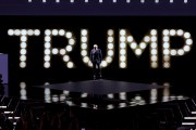 Former President Donald Trump arrives to speak on stage on the fourth day of the Republican National Convention. Behind him, spotlights spells out 