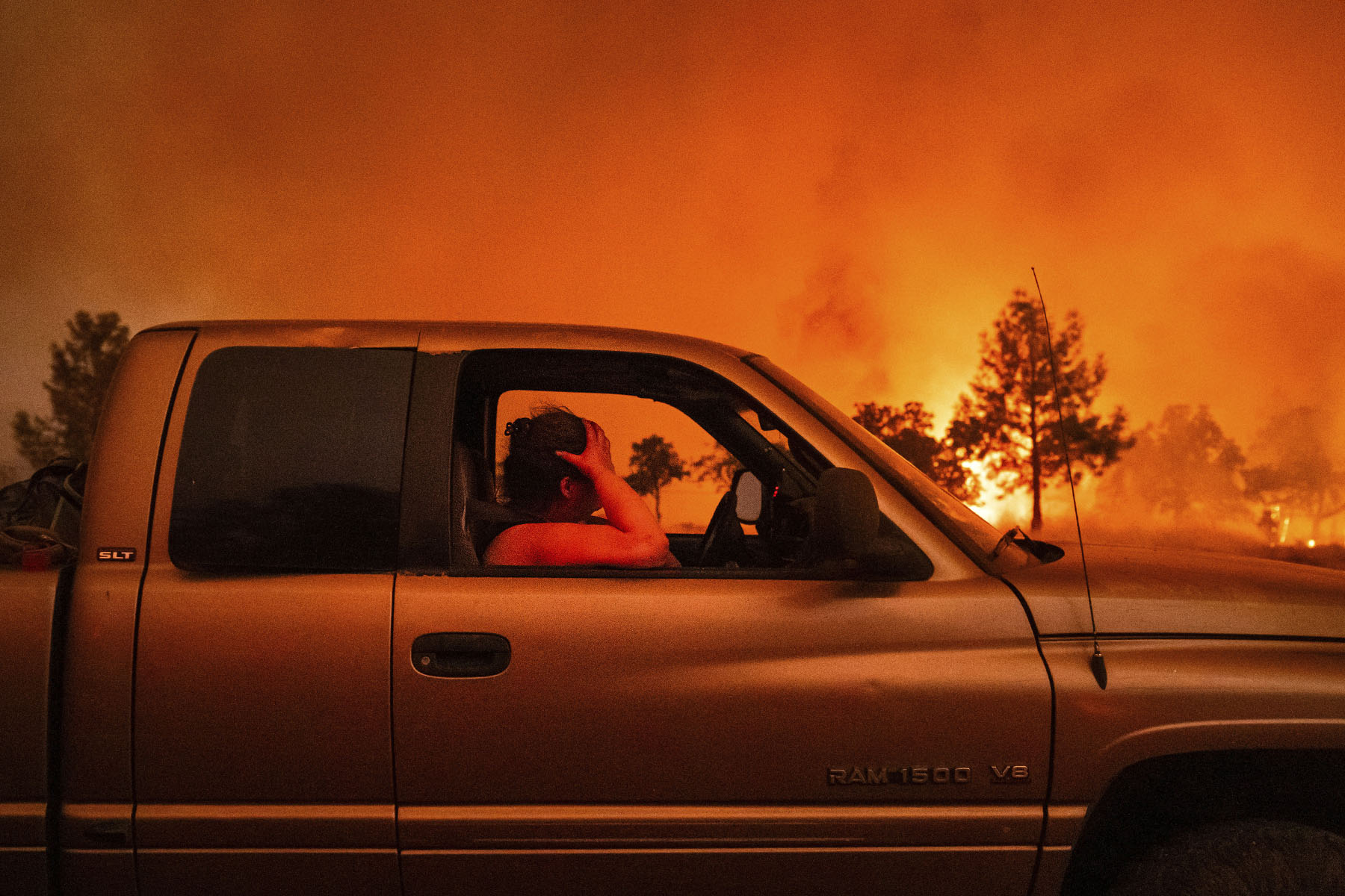 A woman holds her head while evacuating her home as the Park Fire rages in Tehama County, California.