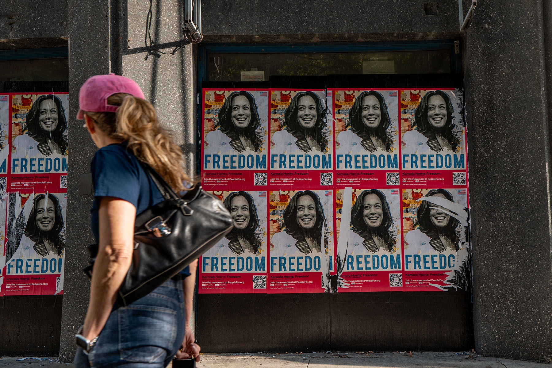 A person walks past posters of Vice President Harris during the first day of the DNC in Chicago, Illinois.