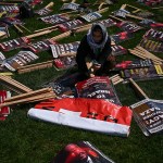 A demonstrator organizes protest signs in a park.
