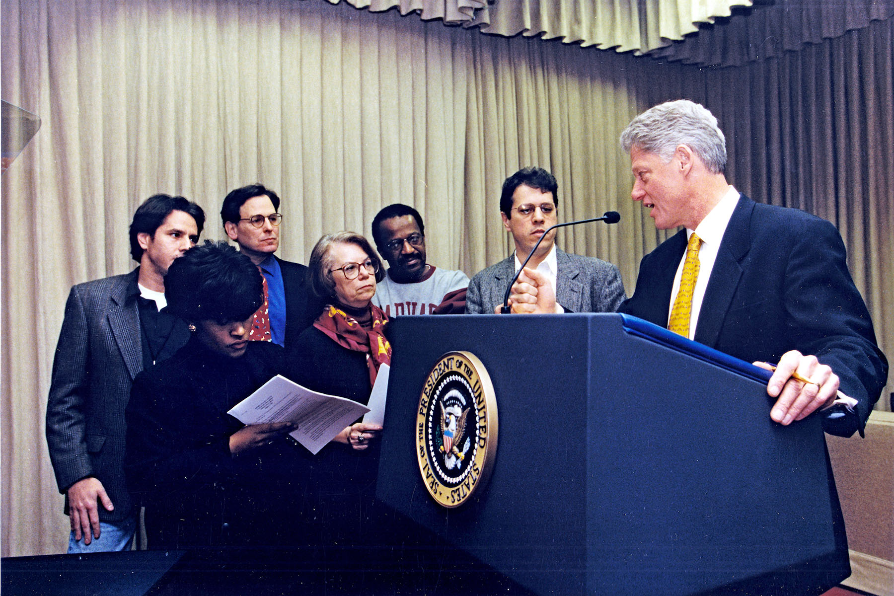 Minyon Moore is seen standing next to a podium with President Bill Clinton and other staffers.