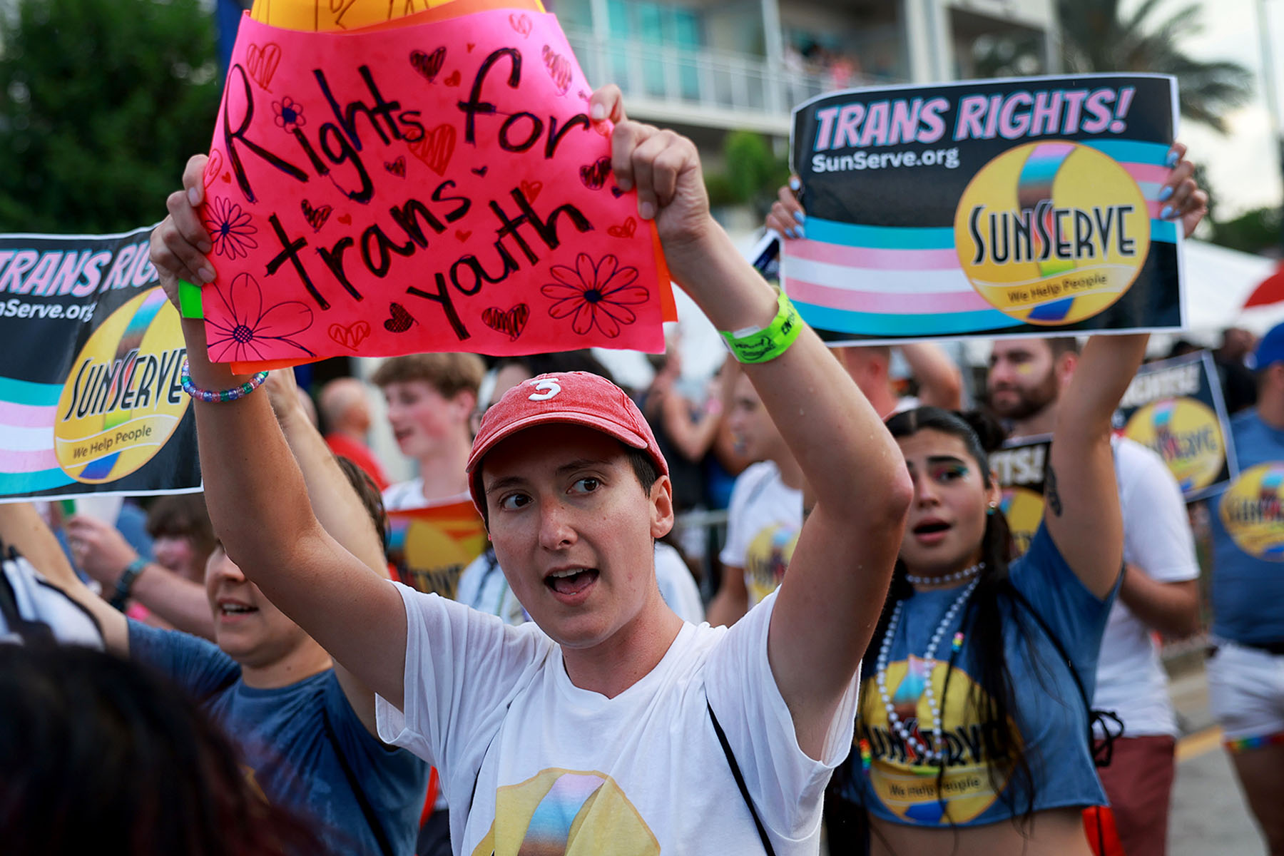 People protesting Florida Gov. Ron DeSantis and Florida lawmakers that passed anti-LGBTQ laws walk in the Stonewall Pride parade. In the foreground, a person holds a sign that reads "rights for trans youth."