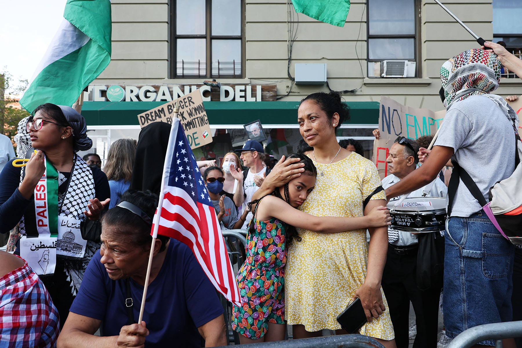 A woman holds a young girl as People gather to protest a campaign event for Democratic presidential candidate Vice President Kamala Harris in New York City.