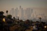 The Los Angeles skyline is shrouded in smog with houses on a hill in the foreground.
