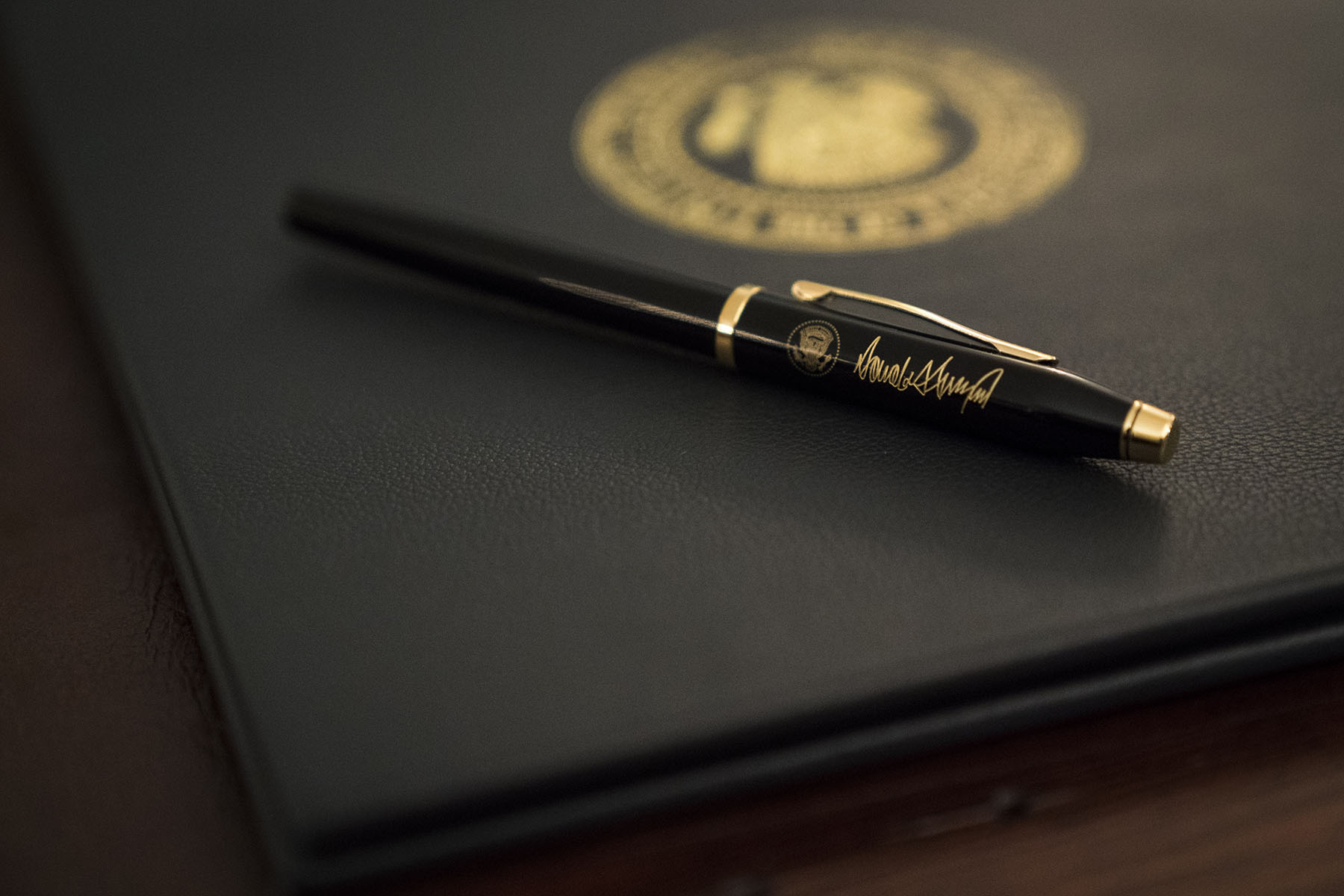 A pen and binder rest on a desk before President Trump signs an executive order.