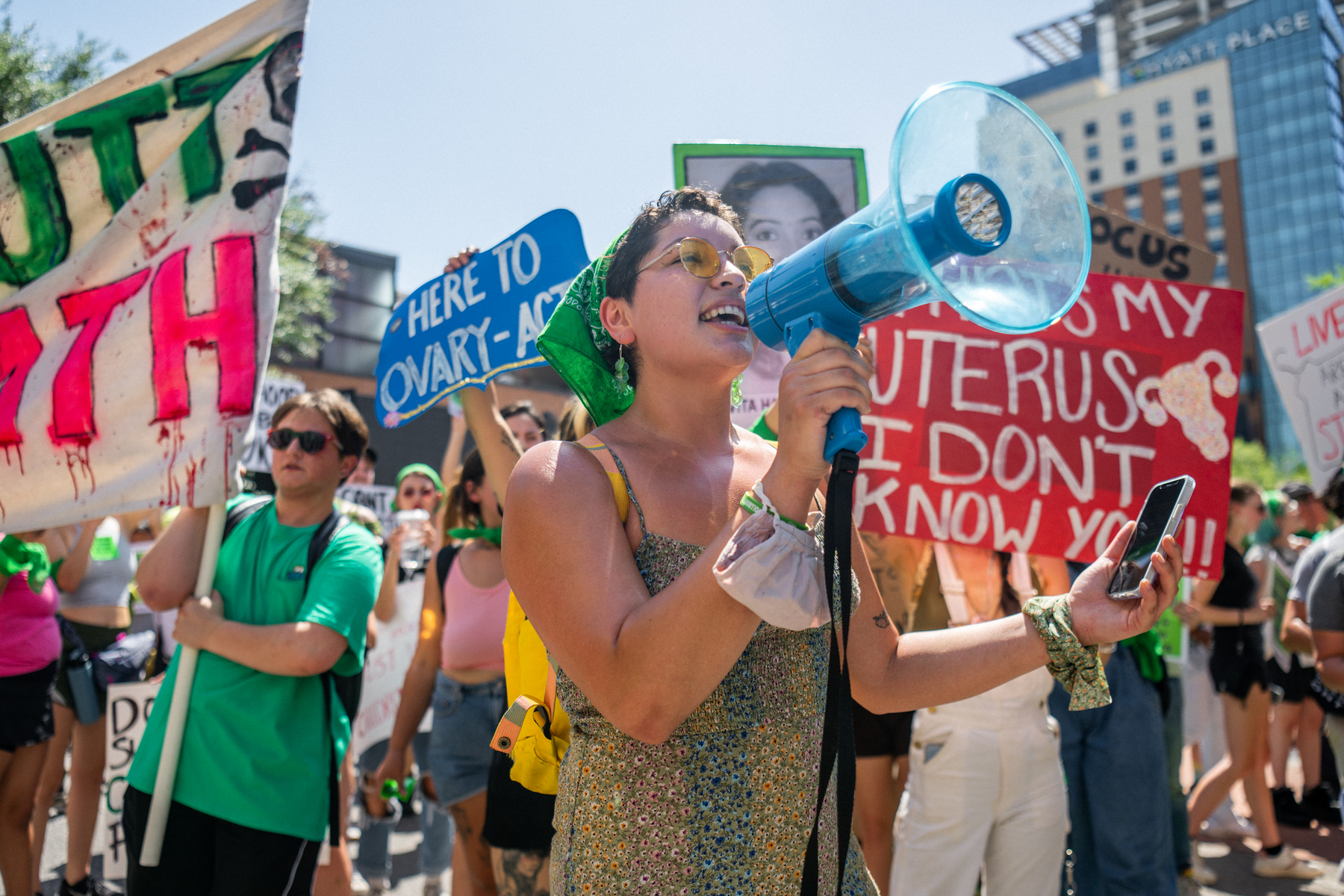 Abortion rights activists and supporters hold signs and speak into a megaphone.
