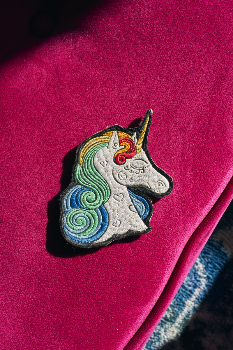 A unicorn patch lays on a bright pink surface.