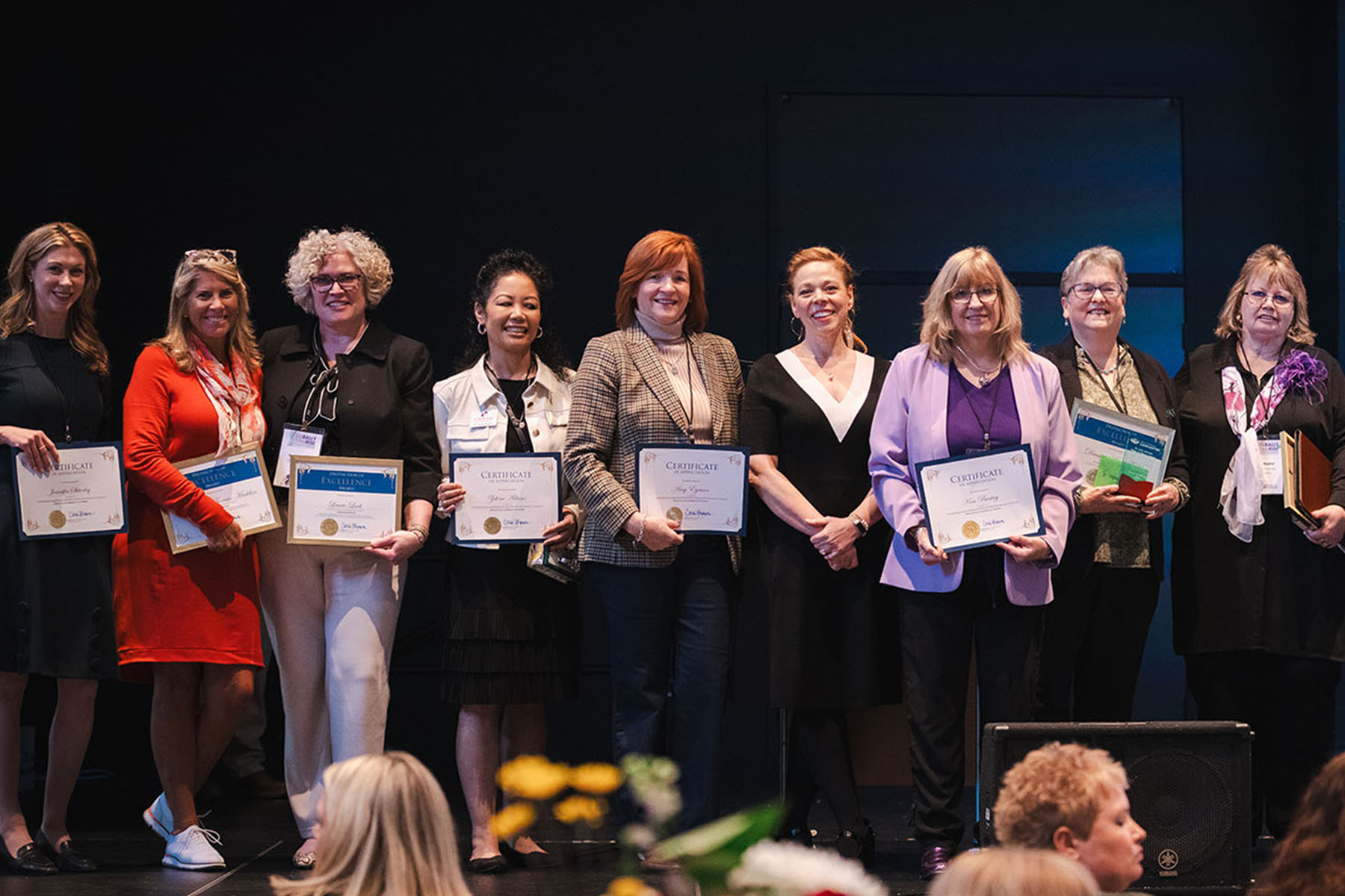 Honorees at the We Rally & We Rise Women’s Conference pose for a group photo on stage.