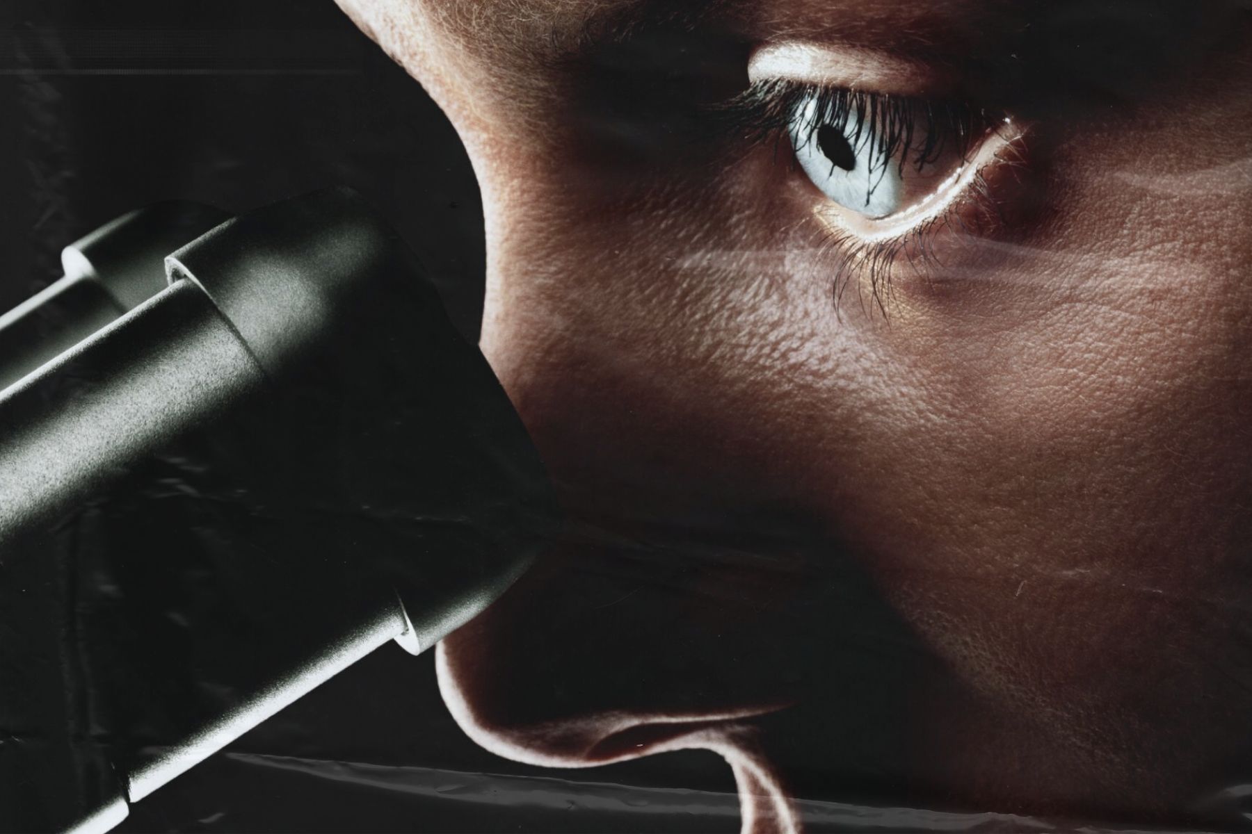 A person peers into a microscope. Their eye is intense and illuminated, framed by dark shadows and a distressed, plastic-like overlay.