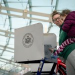 A women holds her daughter as she fills out her ballot at a polling site.