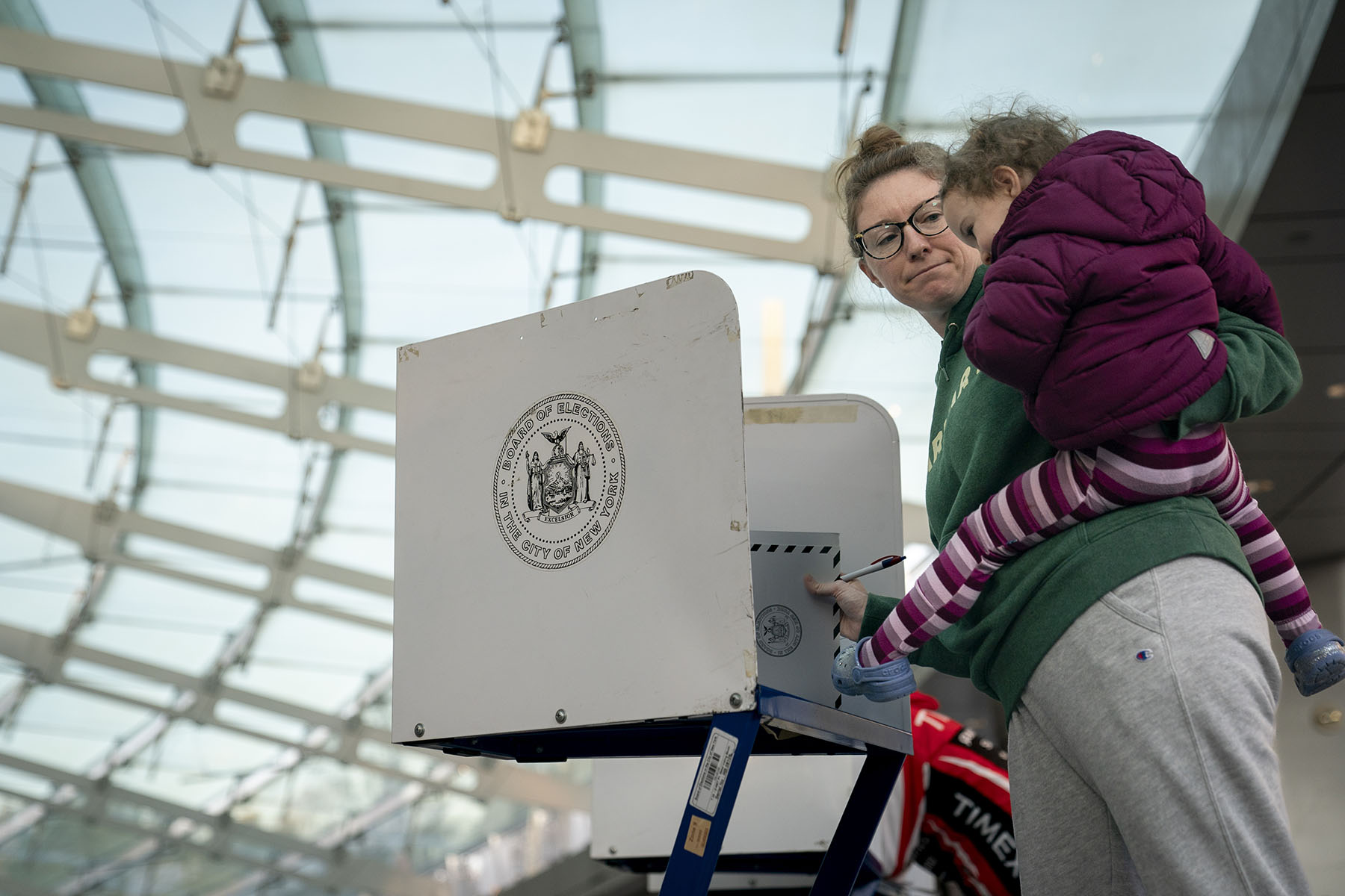 A women holds her daughter as she fills out her ballot at a polling site.