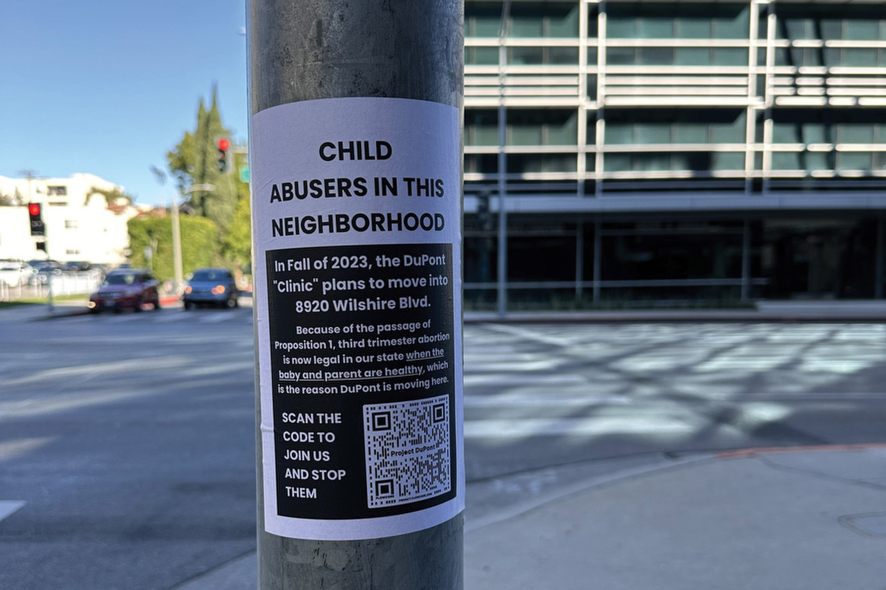 A flyer saying "child abusers in this neighborhood" is on a street light pole.