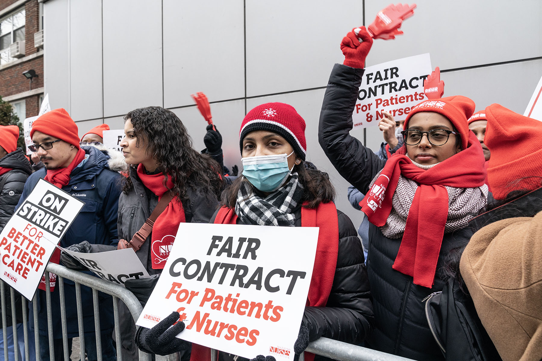 Nurses in red hats and scarves hold signs reading “Fair contract for patients & nurses” during a strike outside Montefiore Medical Center in New York.