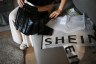 A woman opens an order from fast fashion e-commerce company Shein.