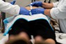 Doctors measure the belly of a pregnant person who lays on a table.