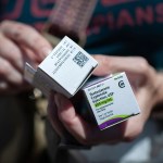 A person holds boxed testosterone prescriptions.