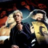 Linda McMahon poses with a raised fist in front of a dramatic WWE poster featuring male wrestlers, including Mick Foley.