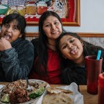 Nine-year-old twins Paola and Elizabeth Guerra eat with their mother Yessenia Ruano at a local Salvadorian restaurant in the family’s neighborhood after church on April 6, 2025, in Milwaukee, Wis. Yessenia has lived in the U.S. for 14 years and is the mother of 9-year-old twin daughters who are U.S. citizens, while working as a teacher’s aide and seeking time to apply for a T visa. She is among many immigrants with no criminal record who now face possible deportation, despite having U.S. citizen family and fears of persecution if returned home.