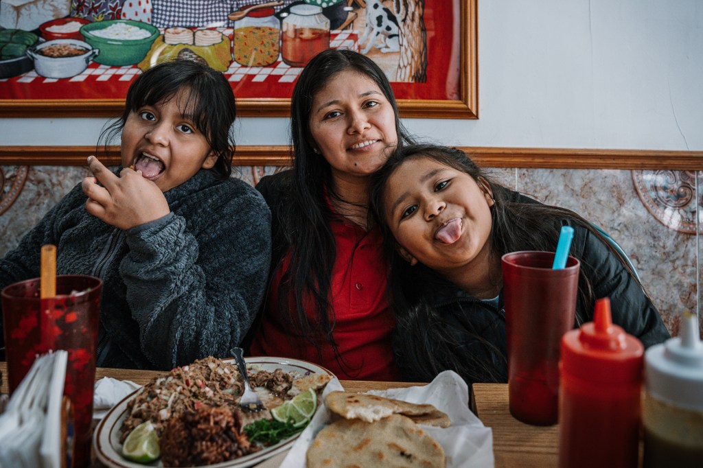 Nine-year-old twins Paola and Elizabeth Guerra eat with their mother Yessenia Ruano at a local Salvadorian restaurant in the family’s neighborhood after church on April 6, 2025, in Milwaukee, Wis. Yessenia has lived in the U.S. for 14 years and is the mother of 9-year-old twin daughters who are U.S. citizens, while working as a teacher’s aide and seeking time to apply for a T visa. She is among many immigrants with no criminal record who now face possible deportation, despite having U.S. citizen family and fears of persecution if returned home.