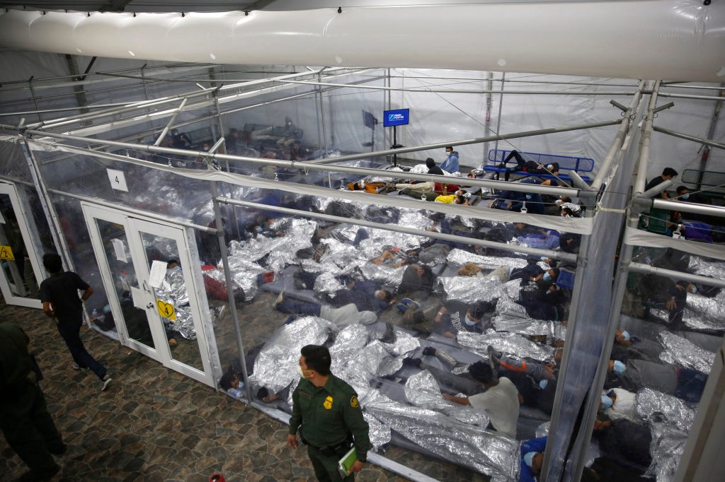 Children lay on the floor with mylar blankets in a holding cell.