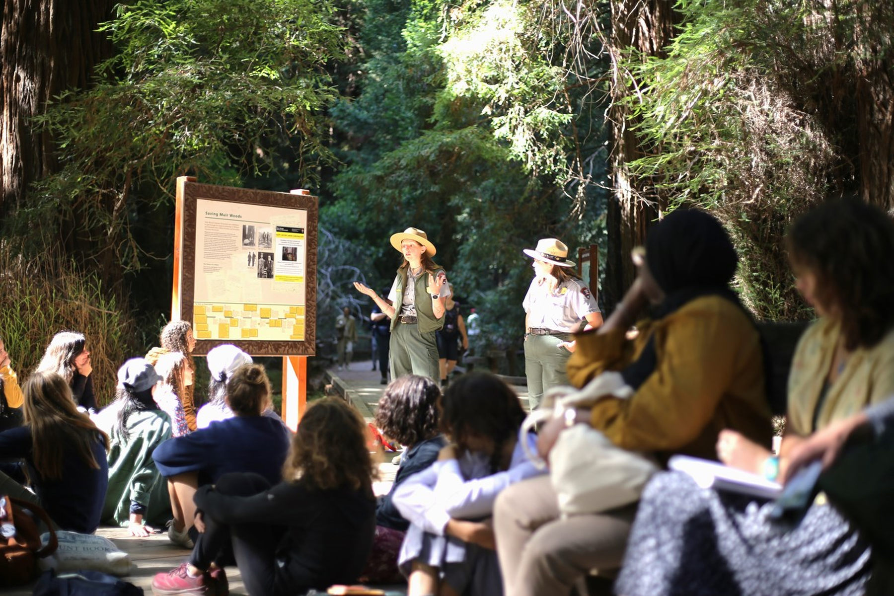 Two rangers talk to a group of park visitors.