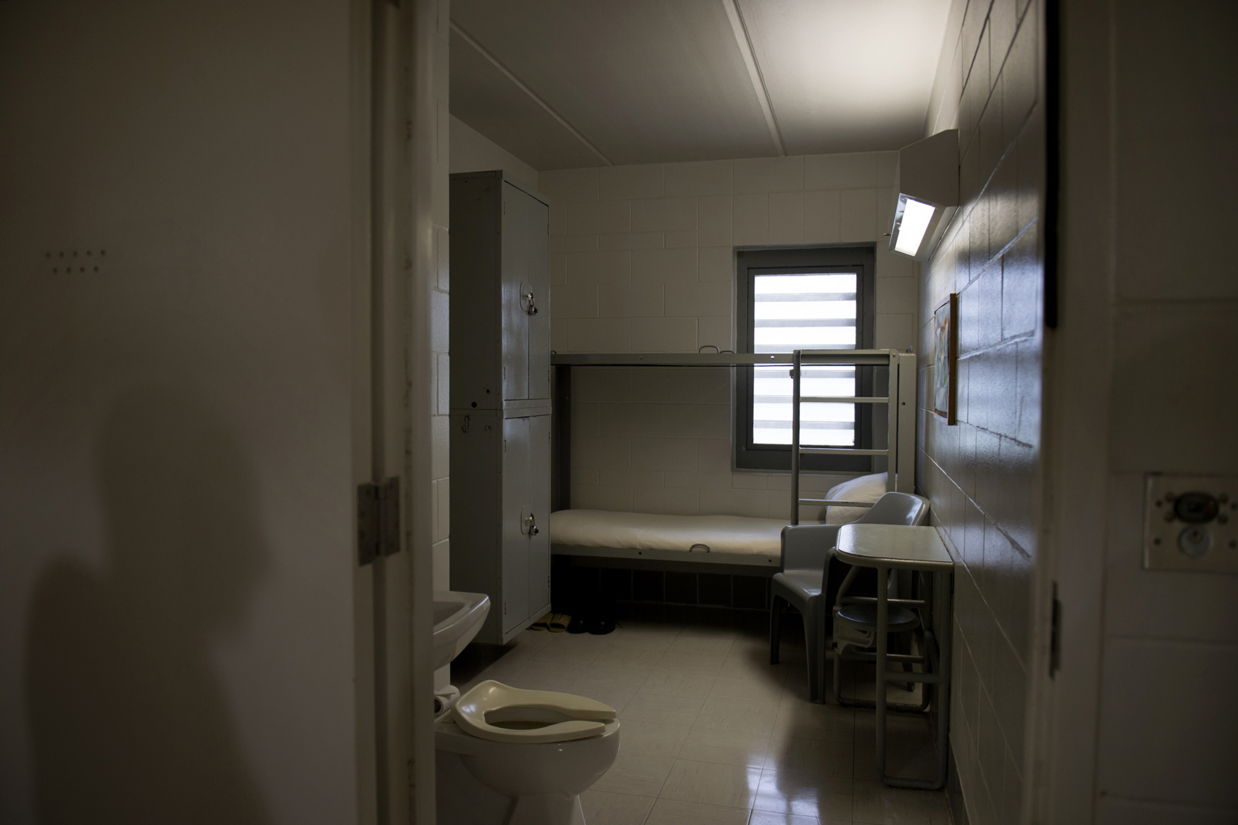 A shadow is cast on the wall outside an empty prison cell